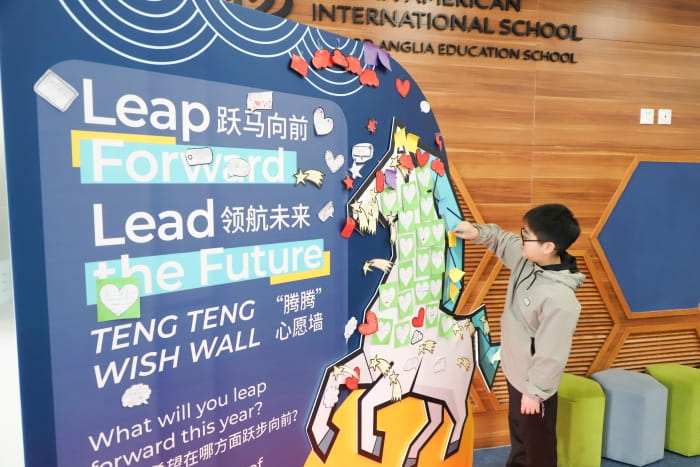 a boy attaching his note to the wishing wall shaped like a horse